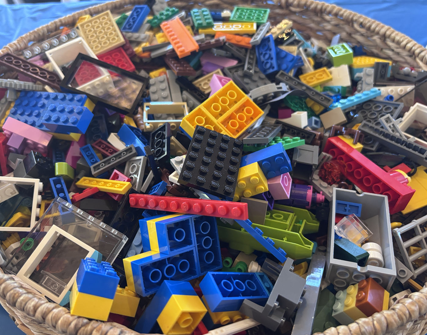 A large woven basket filled with mixed LEGO bricks