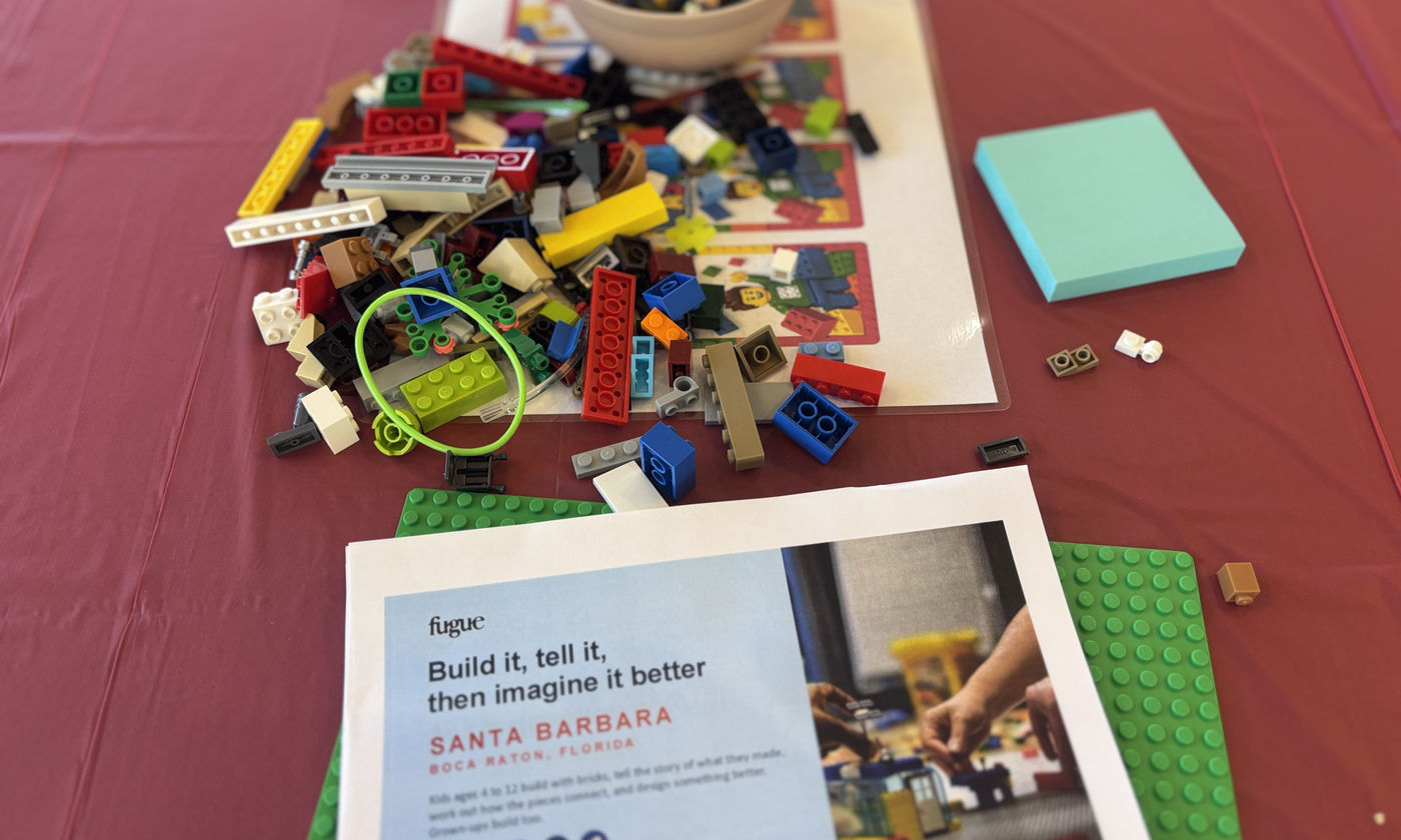 A workshop table set with bricks, a baseplate and a printed challenge card
