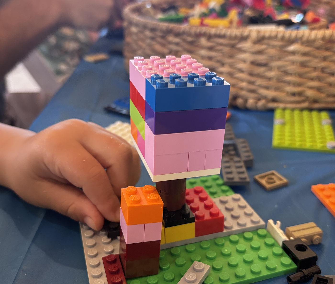 A child's hands placing a brick on a striped LEGO tower